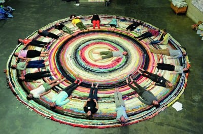 Christian Nagler, Yoga for Adjuncts, 2014, at the Valuing Labor in the Arts Practicum, UC Berkeley Art Museum, April 19, 2014 (photographs © Megan Hoetger, provided by the artist).  Rug: Fritz Haeg, Domestic Integrity Field, 2012–14, crocheted and spirally stitched rug created from local textiles by volunteers, on view January 29–June 1, 2014 (artwork © Fritz Haeg).  The rugs in Haeg’s Domestic Integrities project, which expand as they travel from city to city, function “as charged sites for testing, performing, and presenting how we want to live.”