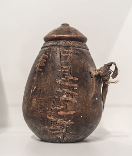 Unidentified artist, Borana (Kenya), vessel for fat or milk, ca.1950s–1970s, wood, leather, basketry, and raffia, showing repairs running along the surface, installed in Made to Move: African Nomadic Design, 2017. Collection of Herbert F. Johnson Museum of Art (photograph by Risham Majeed)