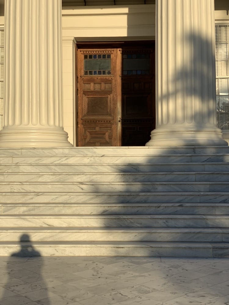 View of the steps at sunset, with the woden door to the Capitol partially open  