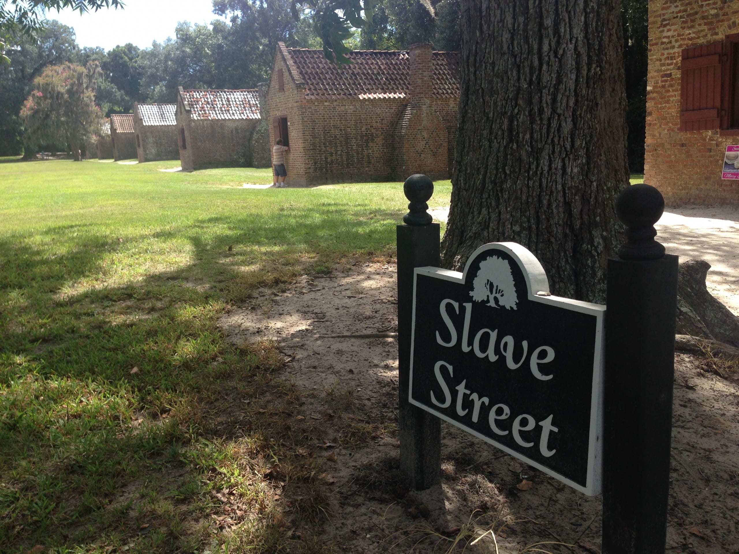 a sign that reads "slave stret" with three cabins in the background