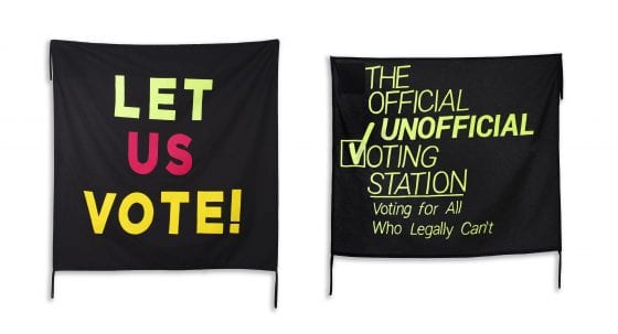 One banner says "Let Us Vote!" in bold, colorful neon letters on a black background; next to it, another banner says "The Official Unofficial Voting Station: Voting for All Who Legally Can’t" in neon green on black