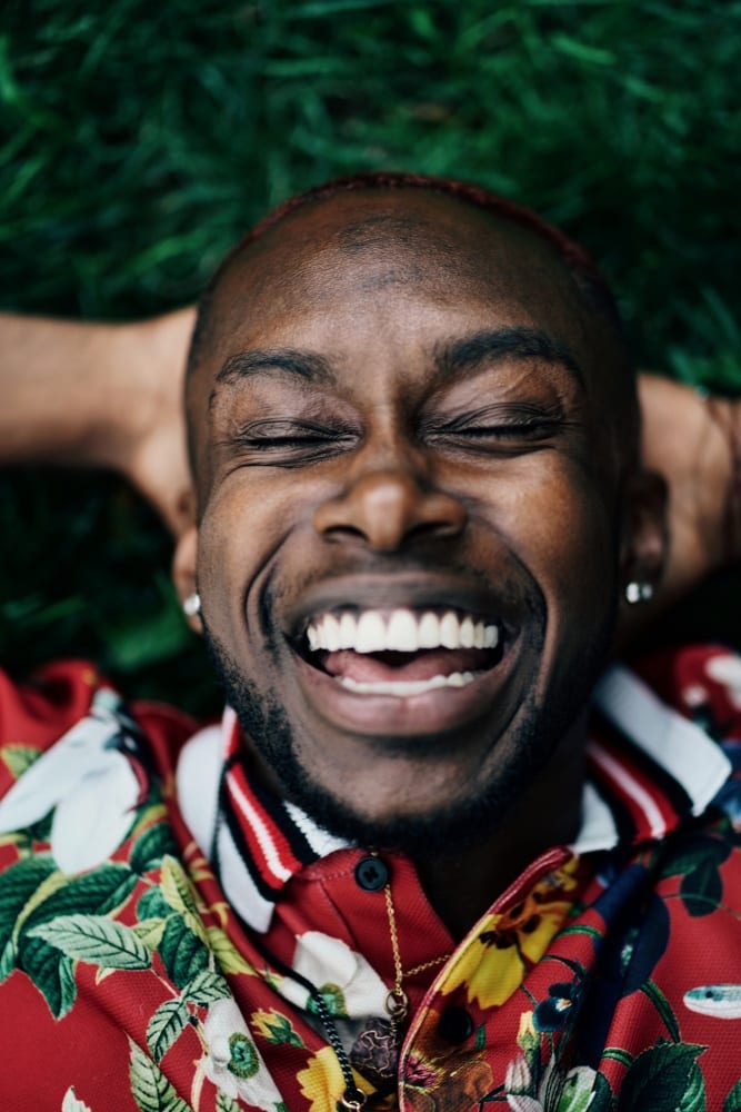 Close-up shot of a man lying on the grass with his eyes closed and his mouth open in a smile