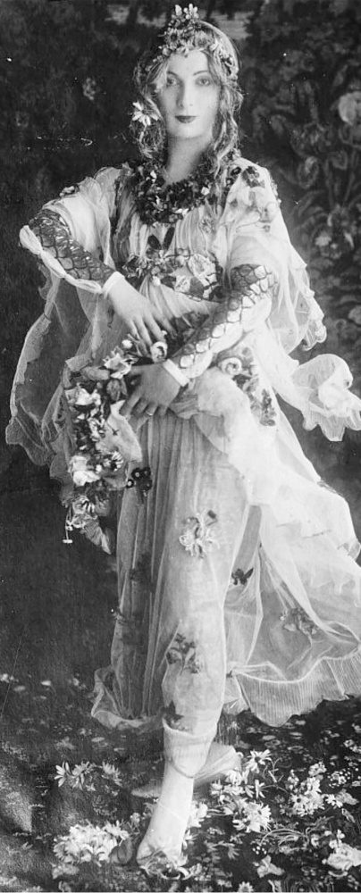 In this photograph, Hazel Lavery is dressed up as Flora from Botticelli's painting Primavera. She wears a dress and head covering with flowers sewn onto them.