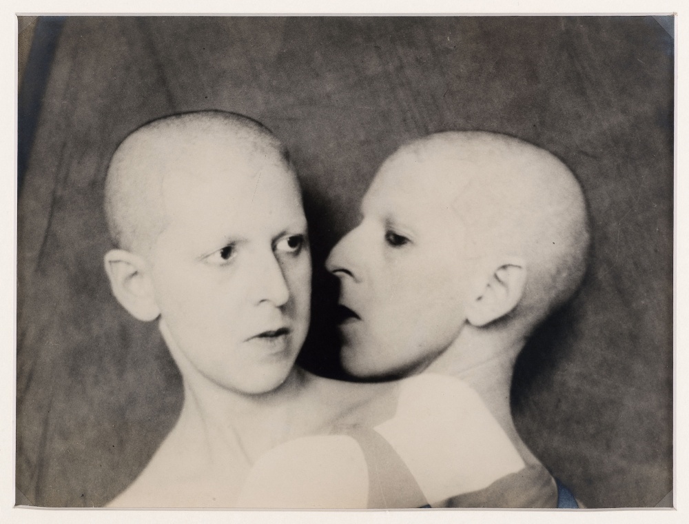 A black-and-white photograph showing a thin white genderqueer Claude Cahun with their back facing the camera and their face in profile.