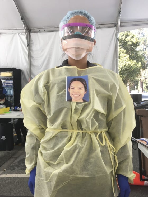 Stanford Express Care nurse Anna Chico, her head and body hidden behind layers of protective gear, wears a smiling portrait affixed over her heart so that people arriving at the COVID-19 testing clinic can see an image of her face