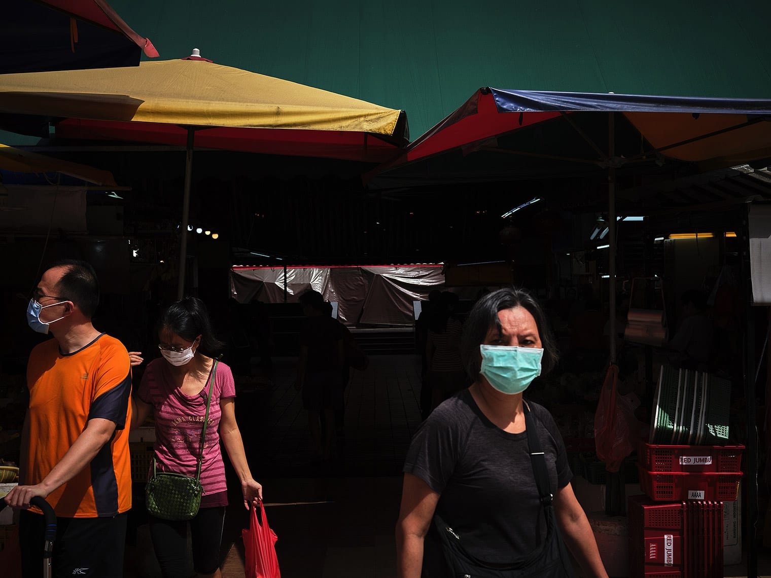 Masked shoppers stand under awnings at a Singapore wet market