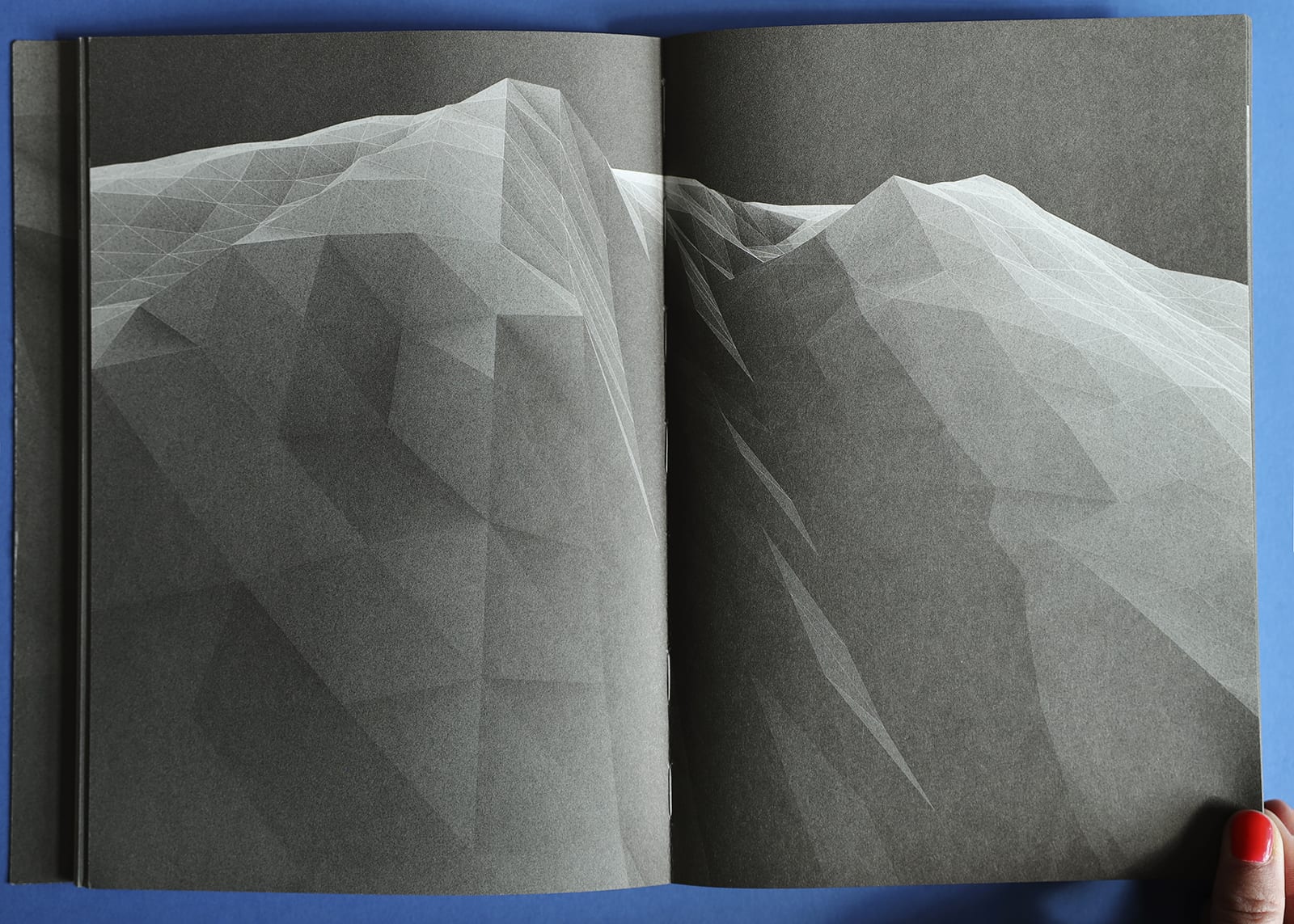 Open-book spread of Imaginary Explosions. Black-and-white graphic of mountain topography.