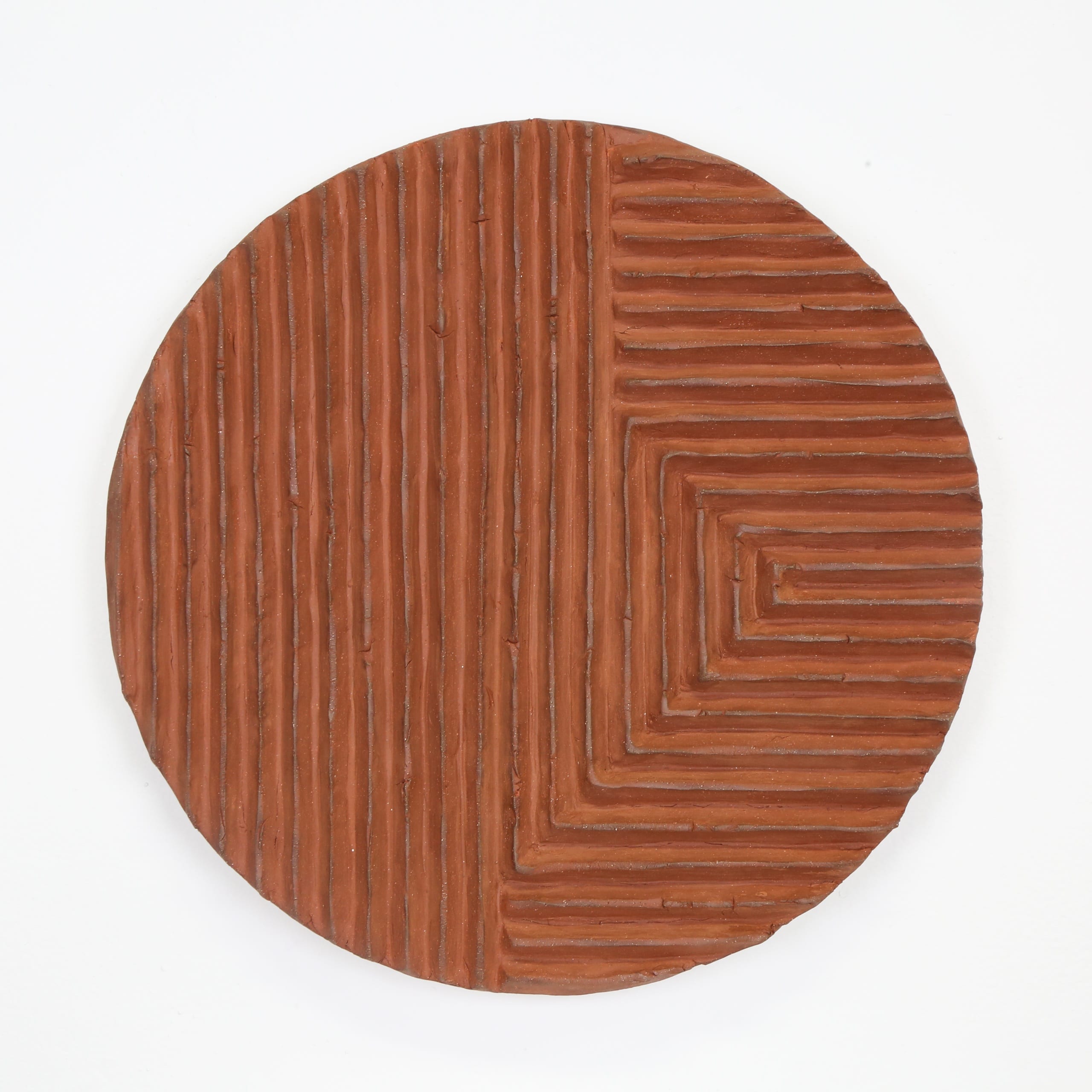Color photograph of a terra-cotta disk with a series of raised, parallel lines sculpted onto its front. The lines run up and down vertically on the left, and toward the object’s right the lines are horizontal. The object appears to be unglazed.