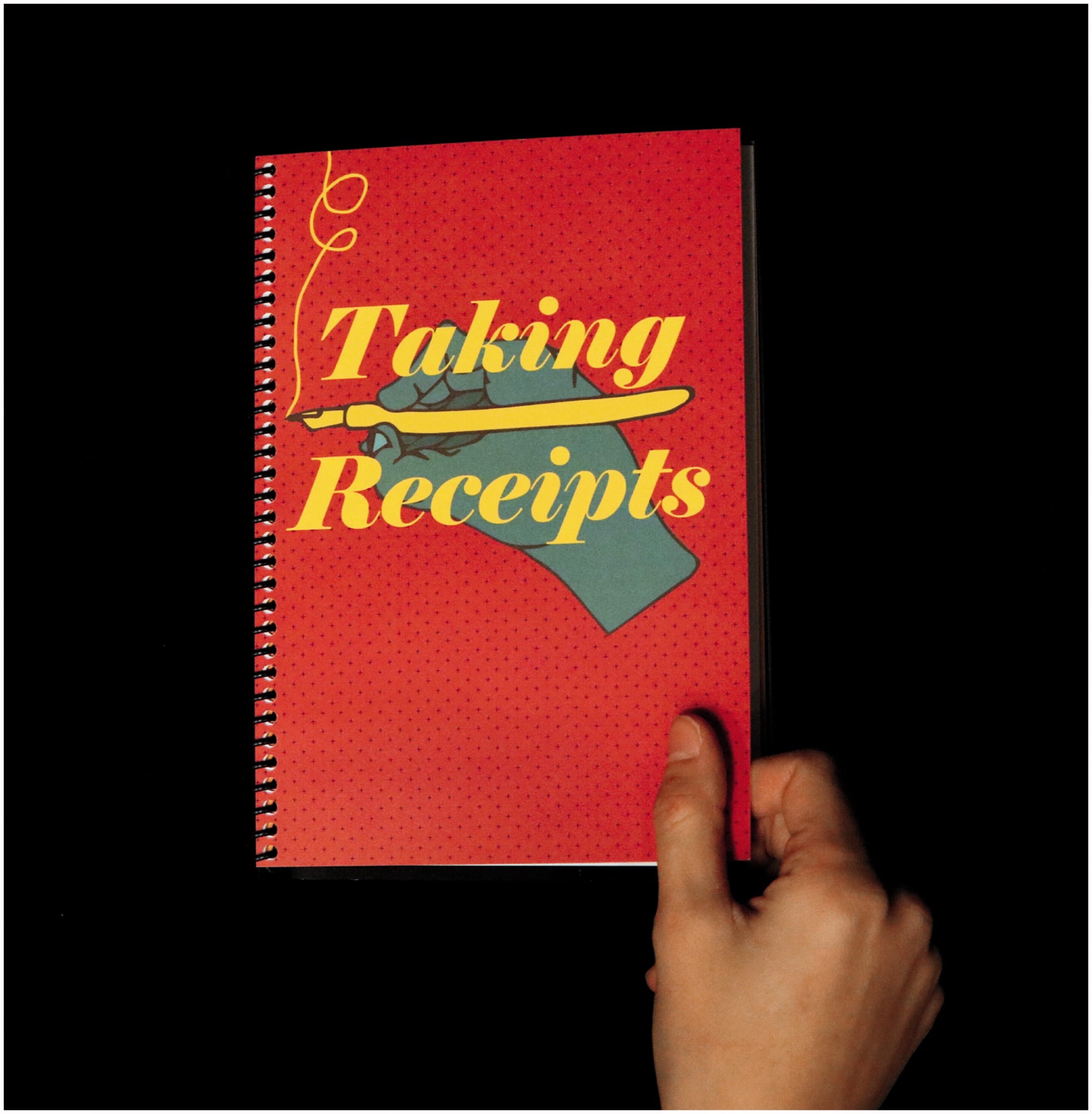 Color photo of a hand opening a spiral-bound notebook. The cover of the notebook is red, and featuers an illustration of a hand drawing something with a yellow pen. The text on the front reads "Taking Receipts."