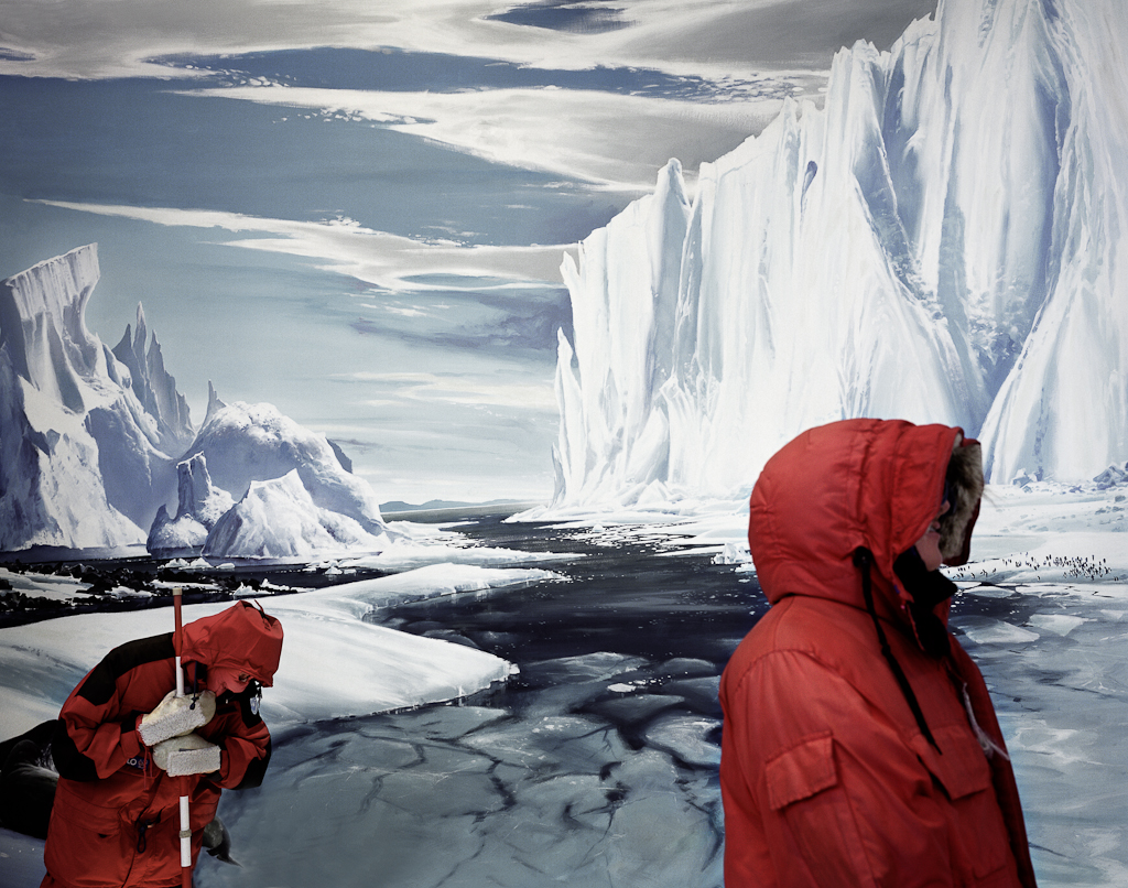 The display in the photograph taken by the artist at the International Antarctic Centre, Christchurch, New Zealand, features two mannequins dressed in extreme weather gear standing before a panoramic photograph of the Barne Glacier in the Antarctic-themed indoor entertainment center